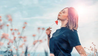 Kvinna i naturen med en blomma – symbol för frihet, självförtroende och välbefinnande vid inkontinens