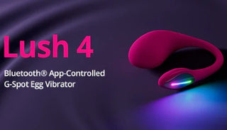 Lovense Lush 4 G-punktsvibrator i rosa med Bluetooth-styrning via app. Produkten är placerad på ett mörklila tyg med ett färgstarkt LED-ljus i änden.