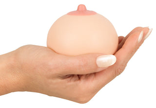 En hand håller i Bröstformad Stressboll, med rosa bröstvårta, mot en vit bakgrund - en perfekt och rolig present till festen.