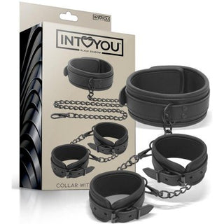 IntoYou Halsband Med Handbojor är ett svart veganskt läderkrage och fasthållningsset med metallkedjor, som erbjuder ett sensuellt utseende. Den inkluderar justerbara handbojor för anpassningsbar komfort och visas både i och utanför förpackningen.