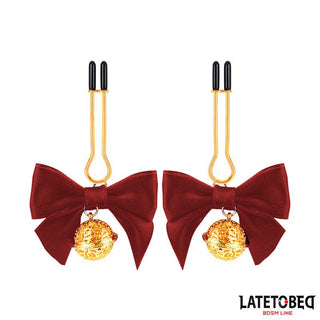 Red Bow Nipple Clamps med justerbara guldklämmor, röda rosetter och dekorativa guldkulor visas på en vit bakgrund.