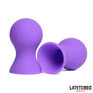 Två Lila Nipple Suckers Silikon vilar på en vit bakgrund, med LATETO BED-logotypen i det nedre högra hörnet.