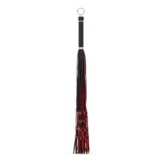 Flogger Piska I PU-Läder 64 cm är en svart och röd bondage-flogger i PU-läder med ett stadigt handtag och en guldring på toppen.