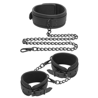 IntoYou Halsband Med Handbojor har handbojor i veganskt läder för handled och nacke som är sammankopplade med mörka metallkedjor för en sensuell look, och erbjuder justerbara handbojor för anpassningsbar komfort.