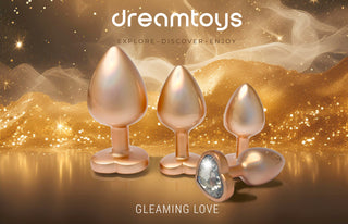 Pärlguld Buttplugg Medium, en skimrande metallisk aluminiumplugg med en juvel, visas på en glittrande pärlguldbakgrund; texten lyder "gleaming love.