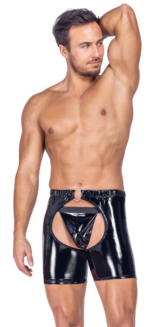 Skjortlös man som poserar med en arm i vädret, iklädd Black Level Vinyl Chaps Set, i glänsande svart material med en stor utskärning framtill.