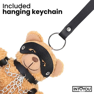 Närbild på Bubu BDSM Teddy Nyckelring: en nallebjörn i svart veganskt läder fästs med en kedja och dekorativ nyckelring, vilket skapar en unik BDSM-inspirerad nyckelringsaccessoar.