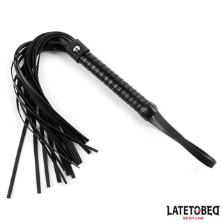 Latetobed Flogger 52 cm är en BDSM-flogger i svart läder med ett omlindat handtag och flera långa svansar som erbjuder varierad stimulering. Visas elegant på en vit bakgrund.