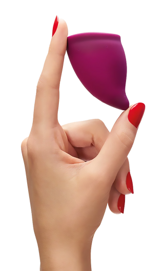 En hand med rött nagellack håller en Fun Cup Menskopp B, tillverkad av allergivänlig silikon av medicinsk kvalitet, mellan tummen och pekfingret.