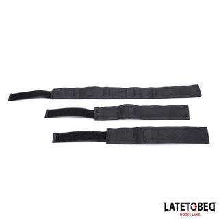 Tre svarta Collar With Wrist Restraints, tillverkade av slitstark nylon med justerbara handtag och kardborreband, visas sida vid sida mot en vit bakgrund.