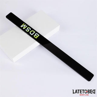 Latetobed Spanking Paddle 38 cm har djärva gula bokstäver och visas diagonalt på ett vitt block, med LATETOBEG-logotypen i hörnet.