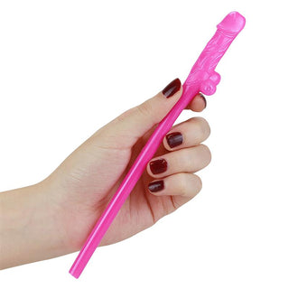 En hand med mörkröda naglar håller en rosa, nyhet ätpinne som påminner om Lovetoy Willy Sugrör Plast 9 st.