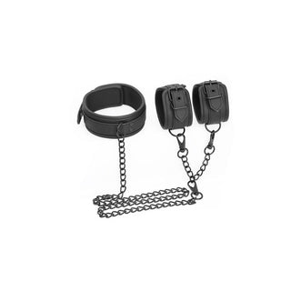 IntoYou Halsband Med Handbojor, gjord av veganskt läder, har en justerbar svart bondagekrage och handbojor sammankopplade med kedjor på en vit bakgrund för en sensuell look.