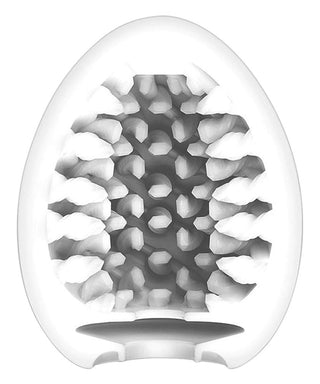 Vitt ovalt föremål med bikakeliknande insida och öppen botten, som liknar ett abstrakt ägg - liknande Tenga Egg Brush.