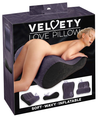 En sammetslen, ergonomisk kilformad uppblåsbar kudde i mörk färg visas på produktboxen Uppblåsbar Sexkudde Velvety.