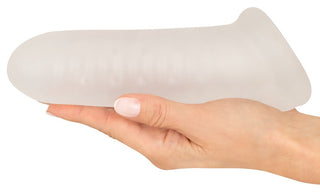 En hand håller Rebel Penissleeve Med Kulring, en penisförlängare i genomskinligt silikon.