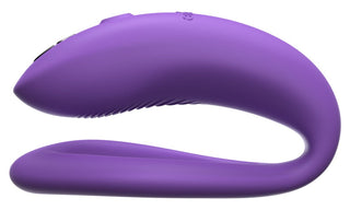 WE-Vibe Sync O Vibrator är en lila, C-formad enhet med en mjuk struktur och ergonomisk design, med en liten metallknapp. Den är kompatibel med We-Vibe-appen för att förbättra dess funktionalitet, visad mot en ren vit bakgrund.