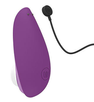 Den eleganta, lila, ovala Womanizer Liberty 2 Luftvibratorn har Pleasure Air Technology. Den har en vit undersida med en logotyp nära botten och kommer med en svart magnetisk laddningskabel som fästs sömlöst i den cirkulära änden.