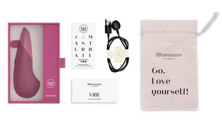 Upptäck Womanizer Vibe Klitorisvibrator, en sexleksaksset med en rödbrun enhet med UltraWave-teknologi, en laddare, guide och förvaringsväska. Älska dig själv!.
