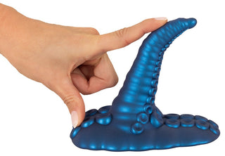 En hand böjer Tentacle Pad Sit On Vibrator, en blå silikonleksak med sugkoppsbas och tentakelliknande design.