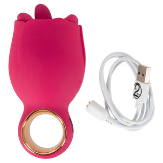 Rosformad stimulator i röd silikon med guldring, visas tillsammans med en vit USB-laddningskabel.