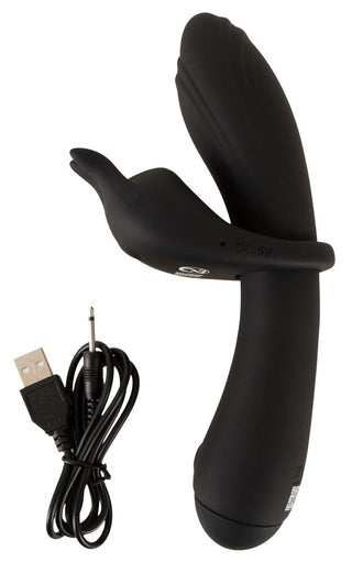 Lila silikonvibrator med två ändar och yttre stimulator, bredvid en USB-laddningskabel på en vit bakgrund.