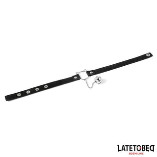 Latetobed Cat Ear Collar, ett svart BDSM-gag med munstycke och kedja i metall, blandar elegans och kant. Kombinera det med en choker eller lekfulla kattöron för en lockande look. Visas på en vit bakgrund - en viktig accessoar.