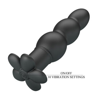 Svart analplugg i mjuk silikon med pärlformad design, blomformad bas och knapp för att välja mellan olika vibrationslägen.