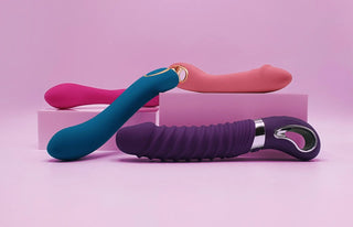 Tre stilrena G-punktvibratorer i olika färger och former placerade på rosa bakgrund med dekorativa block, optimerad för mobilvisning av G-punktvibrator-kategorin