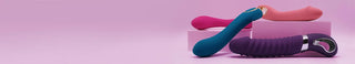 Designade G-punktvibratorer i lila, blått och rosa silikon uppställda på rosa kuber mot rosa bakgrund, idealisk banner för G-punktvibrator-kategorin på dator