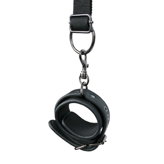 Bondage-setet till sängen inkluderar en svart lädermanschett med ett spänne och metallklämma på en justerbar rem, perfekt för alla bondageuppsättningar, visad på en vit bakgrund.