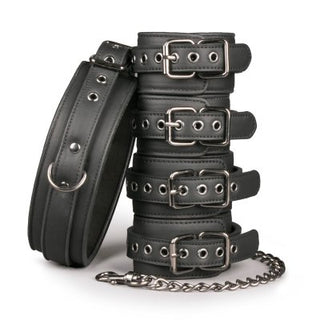 Halsband med fot- och handbojor av svart konstläder, med metallspännen och en kopplingskedja, staplade vertikalt.