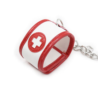 Ohmama 3-delade Nurse Bondage Set har en vit och röd handledsmanschett med en medicinsk korssymbol, fäst vid en silverkedja – perfekt för att utforska förföriska scenarier för rollspel för sjuksköterskor.