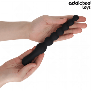 Två händer håller en svart, pärlbeströdd Double Anal Massager 24 cm tillverkad av medicinskt silikon, med Addicted Toys logotyp i det övre högra hörnet.