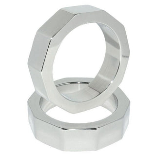 Två Penis- & Pung-Ring i Stål 50 mm, silver och åttkantiga, en stående och en liggande mot vit bakgrund.