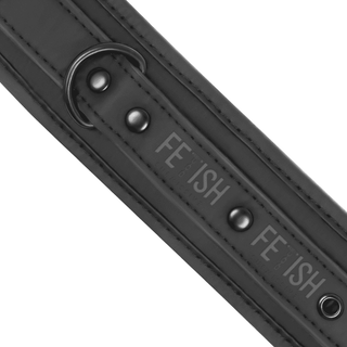 En närbild av svarta veganska läderhandbojor visar nickelfria metalldubbar och en D-ring. Remmen, präglad med "FETISH", ger en edgy touch till din bondage-upplevelse.
