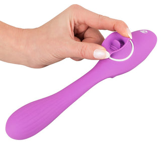 En hand håller graciöst 2 Funktion Vibrator Med Tunga - 22 cm, en lila silikonvibrator designad med en cirkulär ringfunktion för förbättrad G-punktsstimulering.