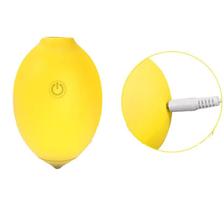 Gul, oval Citron Lemon Luftvibrator i silikon med strömknapp och laddningsport ansluten, visas i närbild.