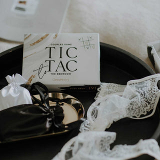 Tic Tac To The Bedroom Premium erbjuder ett romantiskt brädspelsset, med spetsunderkläder och presentpåsar på en bricka för spännande förspelsaktiviteter.