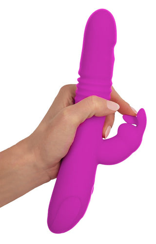 En hand som håller en rosa Thrusting Pearl Rabbit Vibrator, gjord av kroppssäker silikon, mot en vit bakgrund.