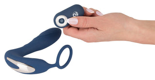 En hand håller i fjärrkontrollen till Prostata Vibrator Med Penisring - Fjärrkontroll, en elegant blå bärbar enhet med en ring.
